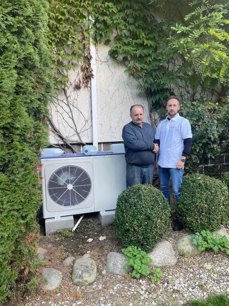 Pompa ciepła zamontowana na posesji przy domu i dwóch panów